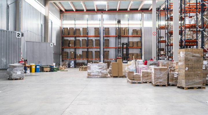 - Innenansicht einer großen Lagerhalle mit Regalen, Paletten und verpackten Waren.
